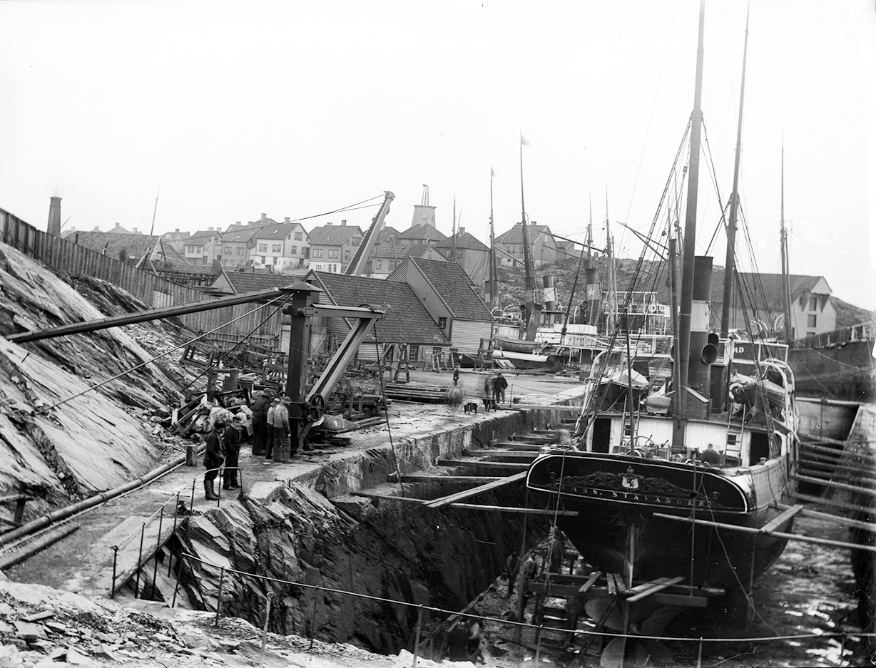 Stavanger Støberi og Dok i Spilderhaugviken ca 1900 til 1910. Bildet er tatt mot nord-vest med vindmøllen i bakgrunnen. Dampskipet ”Imbs” ligger til reparasjon i dokk nr. 2. Kaada/Nor-Hansens samling/Stavanger Byarkiv.
