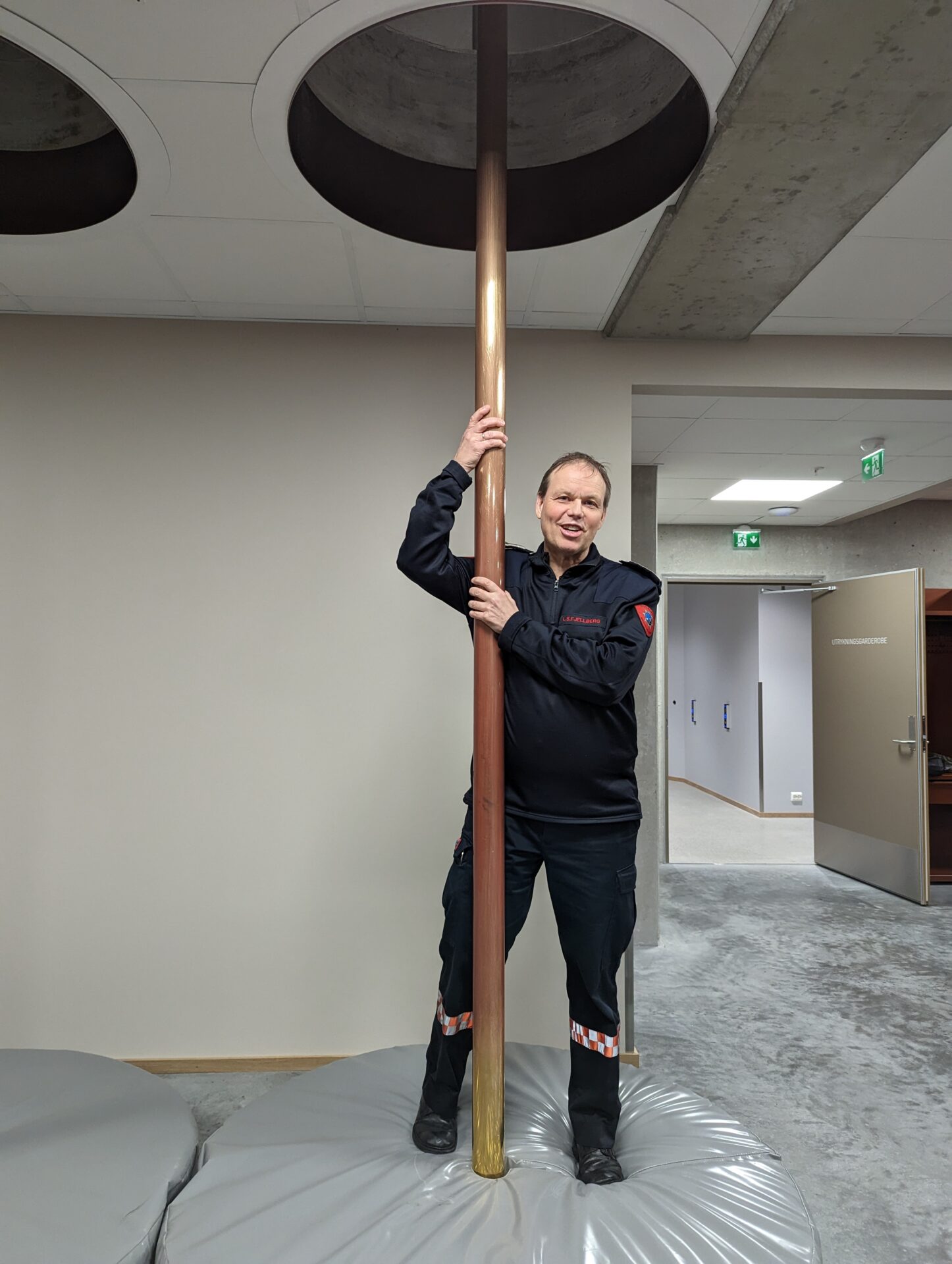 Varabrannsjef Ståle Fjellberg viser fram de gamle brannmannstengene som er på plass mellom etasjene. Disse er fra den gamle stasjonen på Lagårdsveien og er fra 1956.