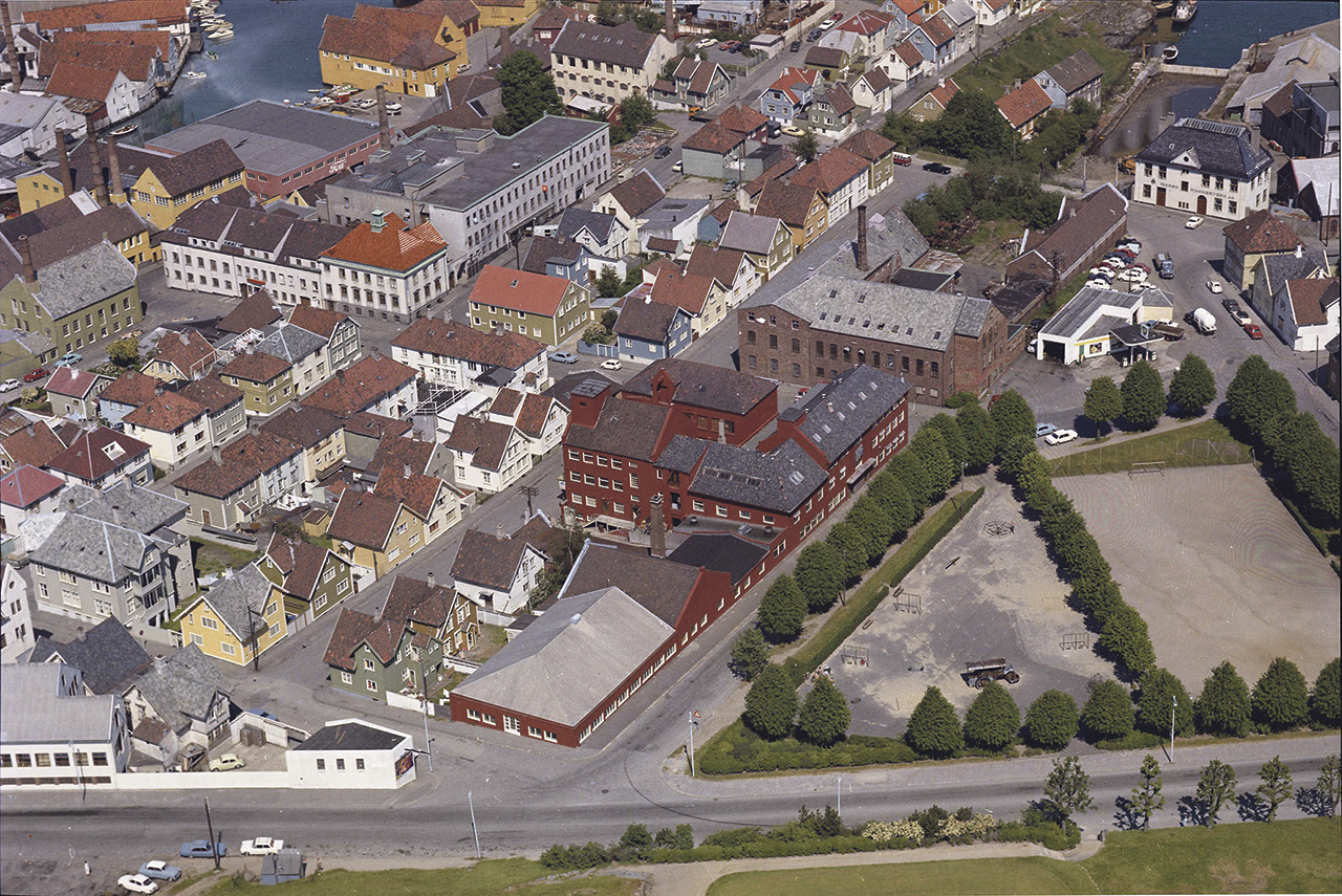 Slik så det ut før Bybrua ble bygd og før Haugesundsgata ble gravd ned i terrenget med kulvert over. De hvite byggene foran til venstre er Stavanger-Fjord Packing. De røde bygningene i midten er Stavanger Gummiindustri også kalt Gummien. Her lå tidligere byens første blikktrykkeri oppført i 1896. Arbeiderboligene i Spilderhauggata 1, 3 og 5 ses i gårdsrommet til Gummien. Mellom Stavanger Støberi & Dok og Gummien ligger Mauritzen såpefabrikk. Widerøes flyfotosamling, Stavanger Byarkiv. Datert 19.6.1970.