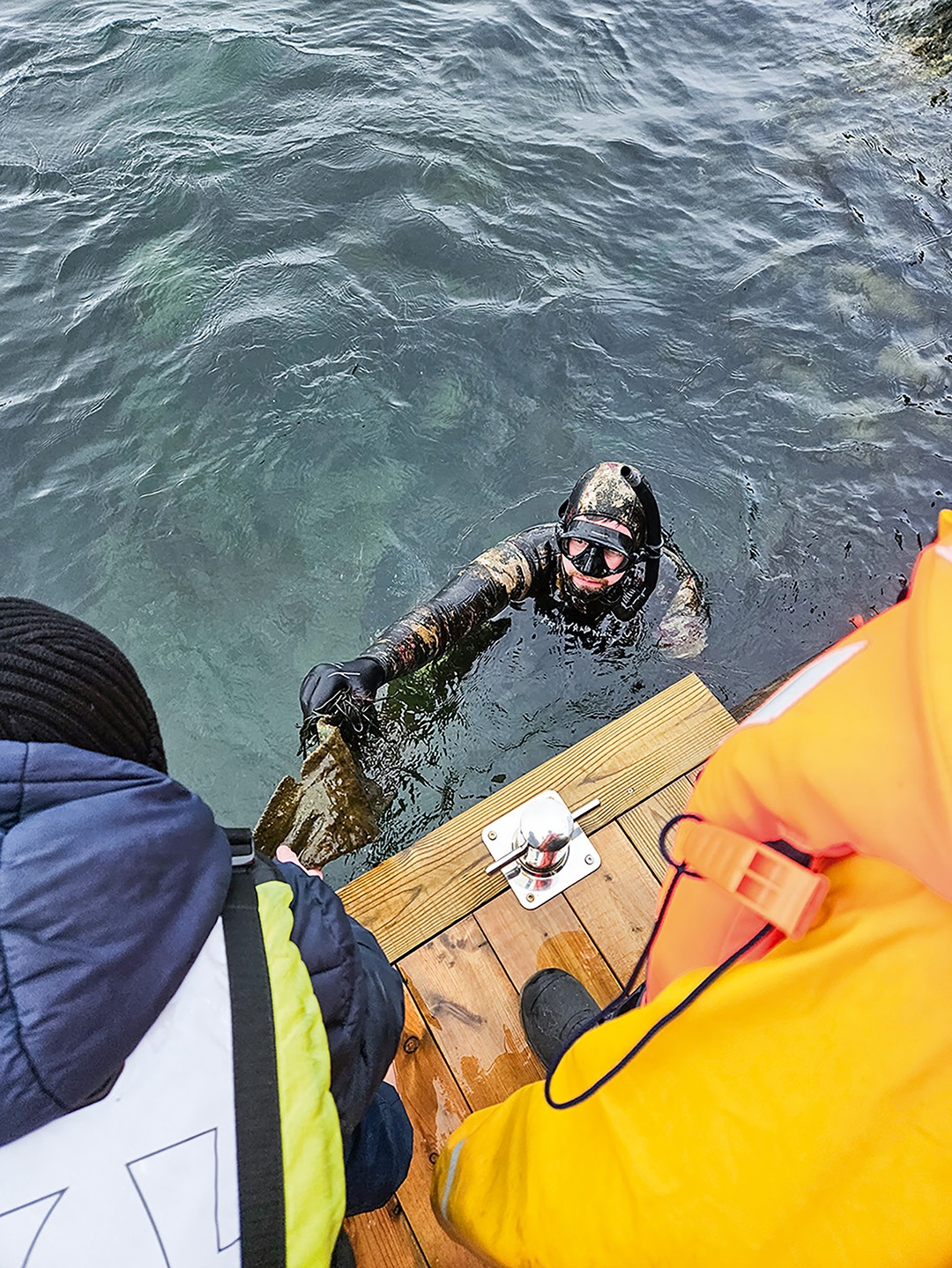 Dykker som leverer søppel til hjelper på land