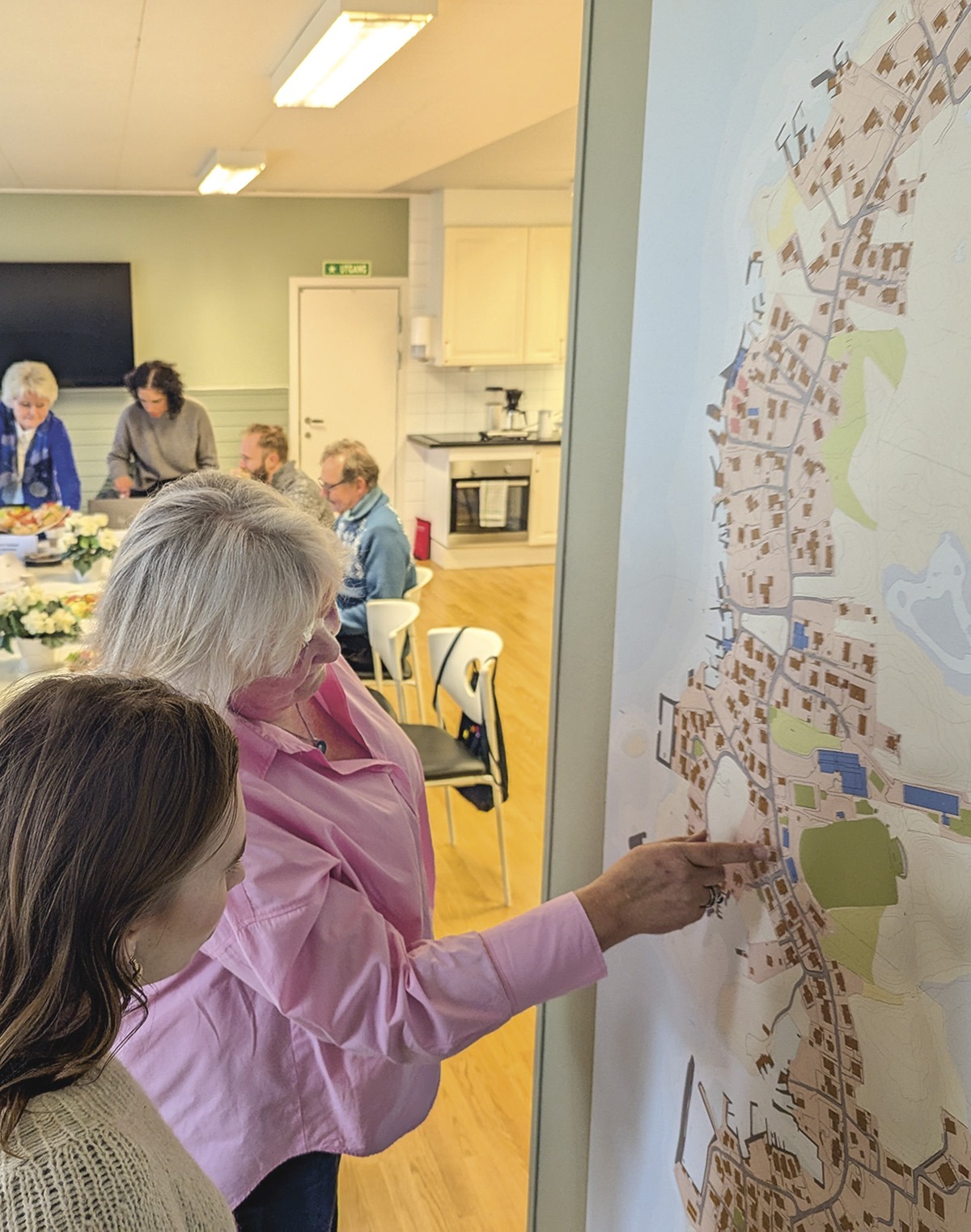 Anne Beth Buch Larsen viser Mia Bruvik hvor det er fantastiske strender, turstier, freesbee bane, hengebro, butikk og brannstasjon på Vassøy. Foto: Sigrid Bækholt.